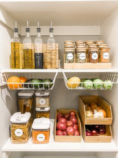 an organized pantry with apples, oranges, and other food items in bins