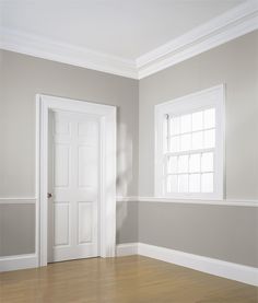 an empty room with two white doors and hard wood floors