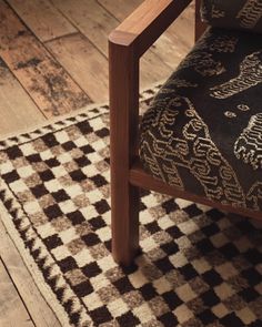 a wooden chair sitting on top of a checkered rug