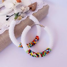 "Stylish white and colorful seed beaded hoop earrings in african style!  ♥ SIZE     Earrings are approximately 2.2\" (5.5 cm) in diameter ♥ 100% handmade ♥ Packed in gift box ♥ Very light ♥ If you like this item in a different color - send me a message, please. Feel free to communicate with me Advice on use and care * Never wear any jewelry while bathing or showering. Chlorine can cause damage. Please do not swim and did not take a shower in beaded jewelry * Try to avoid the drop, shock and compression of jewelry from beads Since this is handmade item, every new good may be vary slightly, but the overall look will match that shown on the photo. The color transfer depends on the settings of your monitor. You can see more hoop earrings in my shop https://www.etsy.com/shop/IvonaHMJewelry?ref= Bohemian White Hoop Earrings For Beach, Festival Colorful Beaded White Hoop Earrings, Festival White Hoop Earrings With Colorful Beads, White Round Hoop Earrings For Festival, Colorful Beaded Circle Earrings For Summer, Colorful Circle Beaded Earrings For Summer, White Hoop Earrings For Festival, White Hoop Jewelry For Summer, Summer Colorful Beaded Circle Earrings