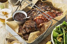 a table topped with lots of food next to drinks and plates filled with meats