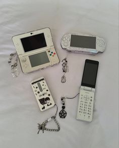 several electronic devices are laid out on a white sheet, including a cell phone and an mp3 player