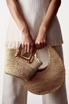 a woman holding a straw bag with her hands