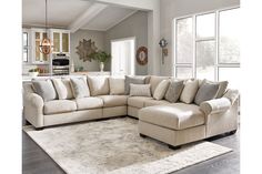 a living room with a large sectional couch and white rug on the floor in front of windows