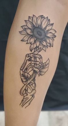 a sunflower and ribbon tattoo on the left leg, which is black and white