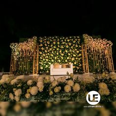 a white couch sitting in front of a lush green wall with flowers and greenery