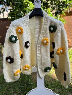 a white sweater with yellow and green flowers on it