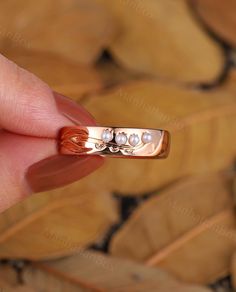 a woman's hand holding a gold ring with pearls