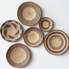 five woven baskets are arranged in the shape of circles on a white surface, each with an individual's own design