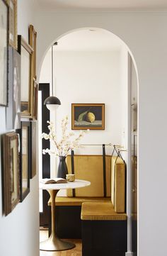 an instagram photo of a yellow chair and table in a living room with pictures on the wall