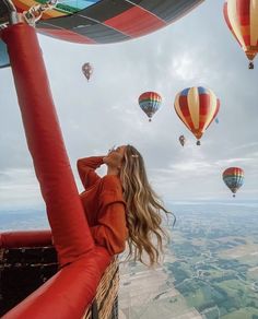 a woman looking up at hot air balloons in the sky