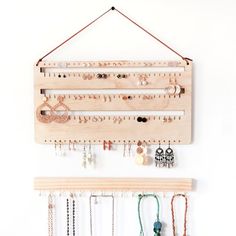 a wall mounted jewelry rack with earrings and necklaces hanging from it's sides