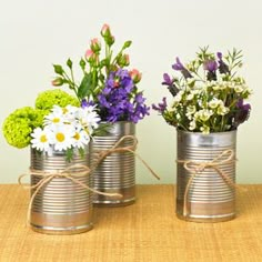 three tin can vases with flowers in them