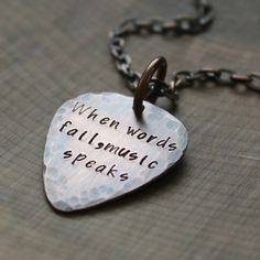 a heart shaped necklace with words on it that says, when words fall music speaks