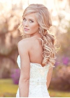 a woman with long blonde hair wearing a wedding dress and looking at the camera while she is