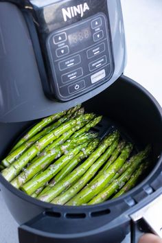 asparagus being cooked in an air fryer with the lid open to show it's freshness