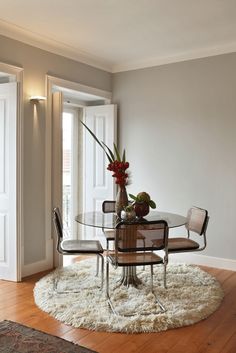 a dining room table with chairs and a vase on top of it in front of a door