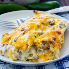 a white plate topped with food next to a casserole dish filled with meat and cheese