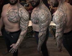 three men with tattoos on their arms and chest are standing in front of a mirror