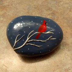 a painted rock with a red bird on it