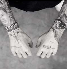 two men with tattoos on their arms holding hands