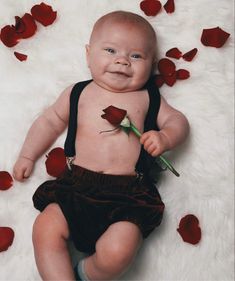 a baby is laying down with a rose in its mouth