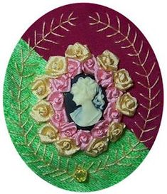 a pink, green and gold brooch with a woman's face in the center