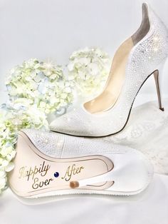 a pair of white high heels sitting next to flowers