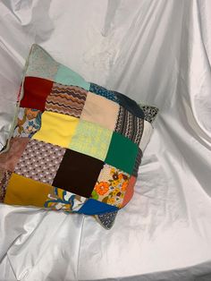 a multicolored patchwork pillow sitting on top of a white sheet