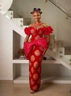 a woman in a red and gold dress standing next to some stairs