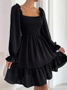 a woman wearing a black dress with long sleeves and ruffles on the bottom