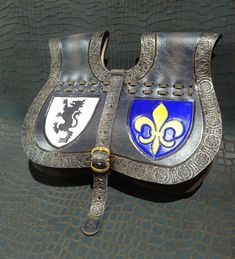 a close up of a silver and blue leather purse on a black surface with gold accents