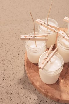 several small jars with toothpicks in them on a wooden platter next to candles