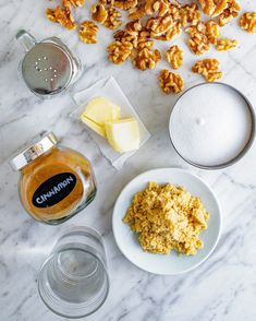 nuts, butter and other ingredients on a marble counter top with glass measuring spoons