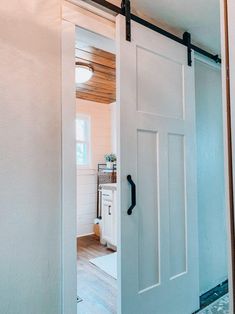 an open door leading to a kitchen with white walls and wood flooring in the background