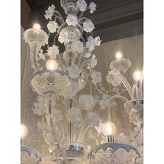 a chandelier with white flowers and lights hanging from it's sides in a room