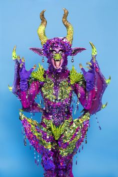 a purple and green costume with horns on it's head is standing in front of a blue background