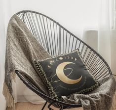 a black and gold pillow sitting on top of a metal chair next to a window