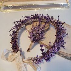 purple flowers are arranged on top of a piece of wood and tied with lace ribbon