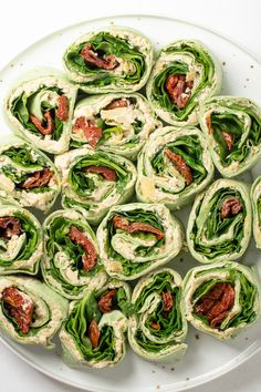 a plate filled with rolls covered in lettuce and bacon