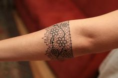 a woman's arm with a tattoo on it that has flowers and leaves drawn on it