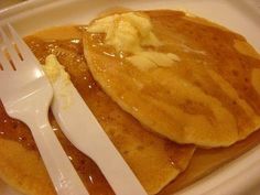 pancakes with butter and syrup are on a white plate, ready to be eaten by someone