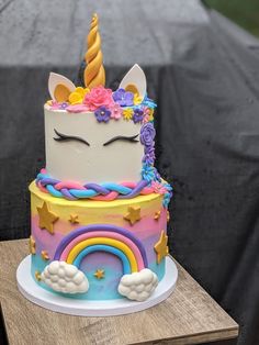 there is a cake with a unicorn face on it and rainbow decorations around the edges