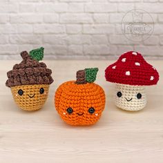 three small crocheted pumpkins with faces on them sitting next to each other