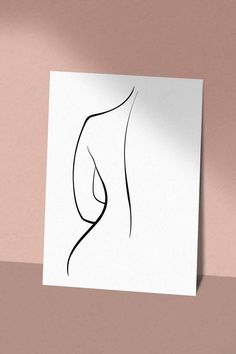 a piece of paper with a drawing of a woman's body on it, against a pink wall