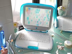 an open laptop computer sitting on top of a glass desk next to a sink and window