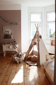 a child's teepee in a room with wood flooring and striped walls