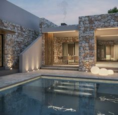 an outdoor swimming pool with stone walls and steps leading up to the house's entrance