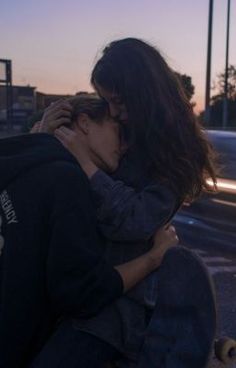 two people hugging each other on the street