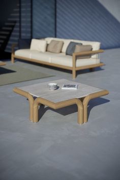 a coffee table sitting on top of a cement floor next to a couch and chair